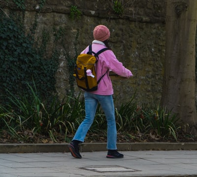 Wearing pink hoodie and a woman walking along the sidewalk, the blue denim jeans
